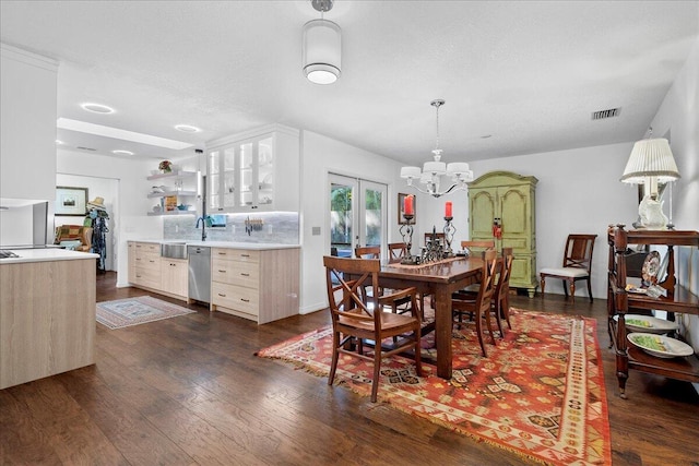 dining area featuring french doors, dark hardwood / wood-style flooring, a textured ceiling, and an inviting chandelier