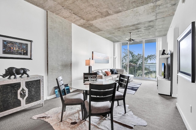 dining space featuring carpet flooring, ceiling fan, and a wall of windows