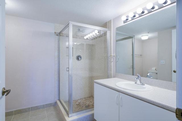 bathroom featuring tile patterned flooring, vanity, toilet, and walk in shower