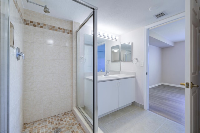 bathroom featuring tiled shower, hardwood / wood-style floors, vanity, and a textured ceiling