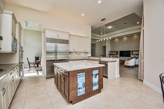 kitchen with tasteful backsplash, hanging light fixtures, a center island, built in appliances, and kitchen peninsula