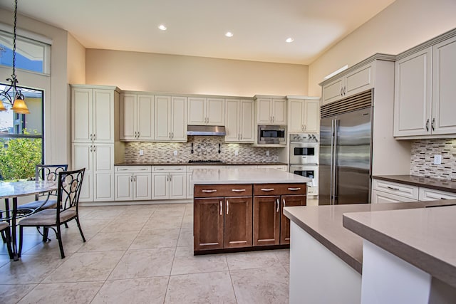 kitchen with built in appliances, decorative light fixtures, light tile patterned floors, a notable chandelier, and decorative backsplash