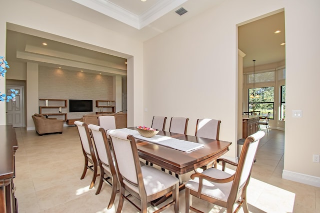 tiled dining room featuring a tray ceiling and ornamental molding