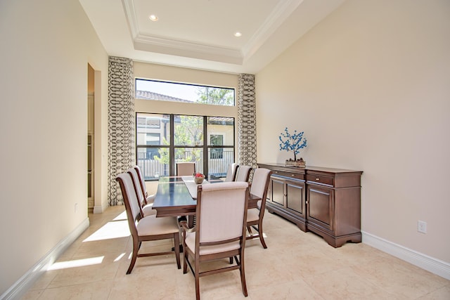 tiled dining space featuring a raised ceiling and crown molding