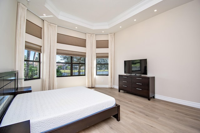 bedroom featuring ornamental molding, a raised ceiling, and light wood-type flooring