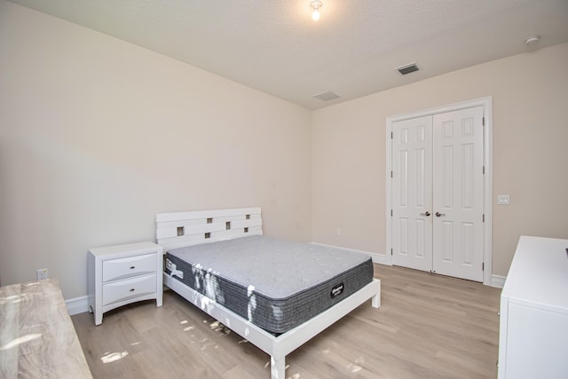 bedroom featuring light hardwood / wood-style floors, a closet, and a textured ceiling