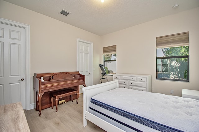 bedroom with light hardwood / wood-style flooring and a textured ceiling