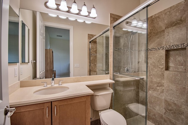 bathroom with vanity, a shower with shower door, and toilet