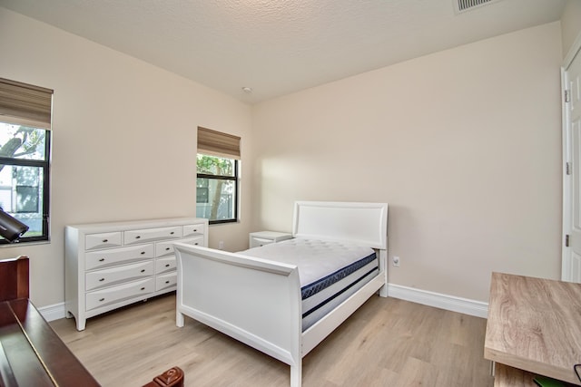 bedroom with multiple windows and light wood-type flooring