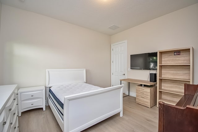 bedroom with light hardwood / wood-style flooring and a textured ceiling