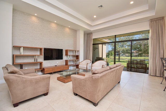 tiled living room featuring a tray ceiling and a towering ceiling