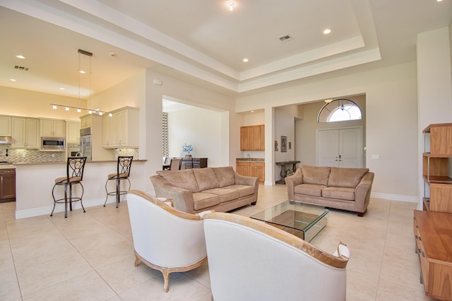 living room featuring light tile patterned flooring, a tray ceiling, and a high ceiling