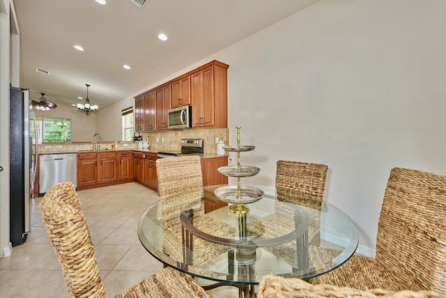 tiled dining space with sink, vaulted ceiling, and an inviting chandelier