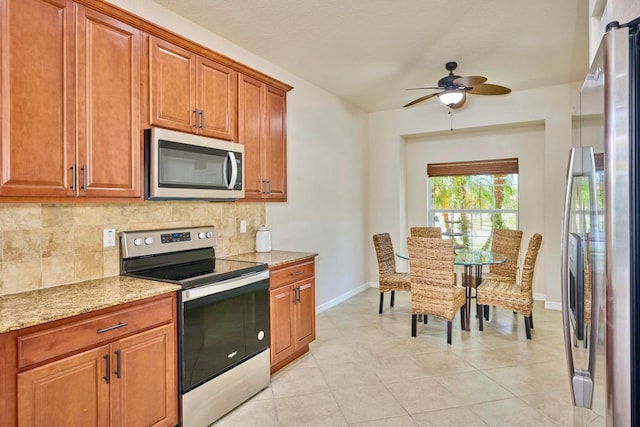 kitchen featuring decorative backsplash, light stone countertops, stainless steel appliances, ceiling fan, and light tile patterned flooring