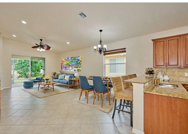 tiled dining room featuring plenty of natural light, sink, and ceiling fan with notable chandelier