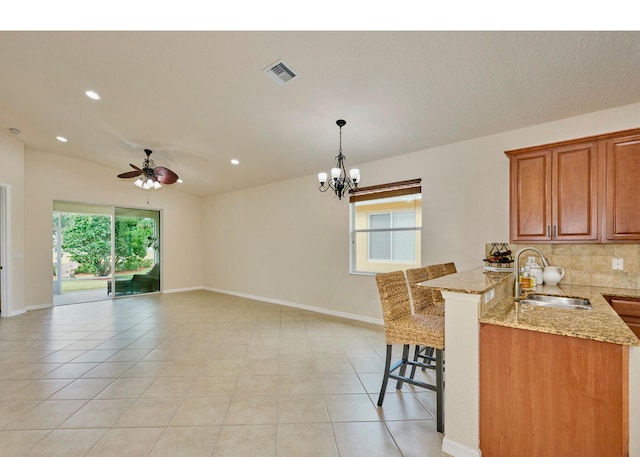 kitchen with kitchen peninsula, light stone counters, sink, and plenty of natural light