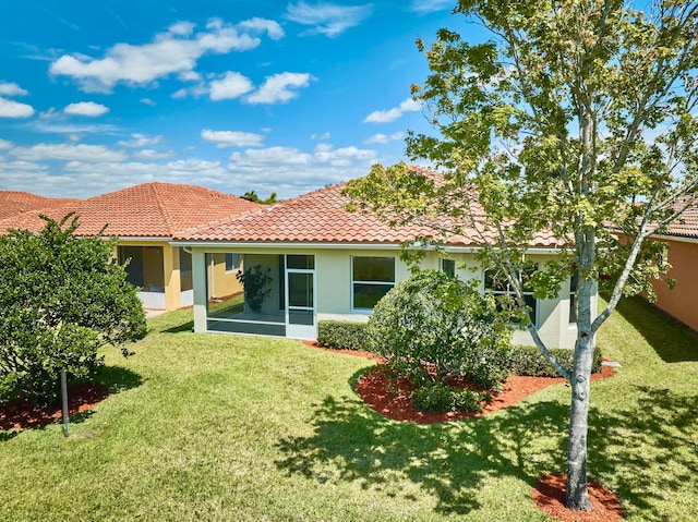 rear view of house featuring a sunroom and a yard