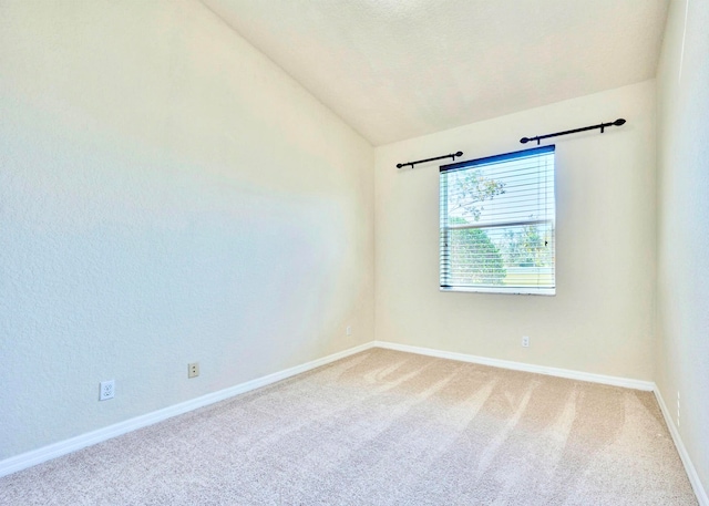 carpeted empty room with vaulted ceiling