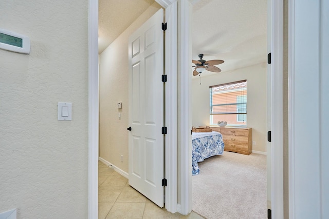 hallway with a textured ceiling and light carpet