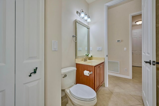 bathroom with toilet, vanity, and tile patterned floors