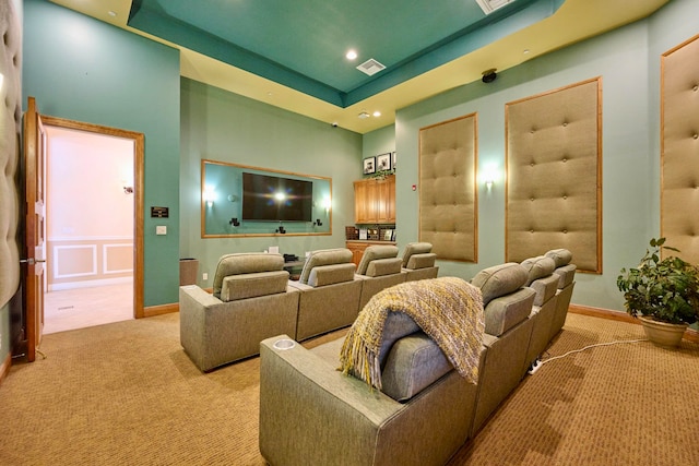 home theater featuring light colored carpet, a towering ceiling, and a tray ceiling