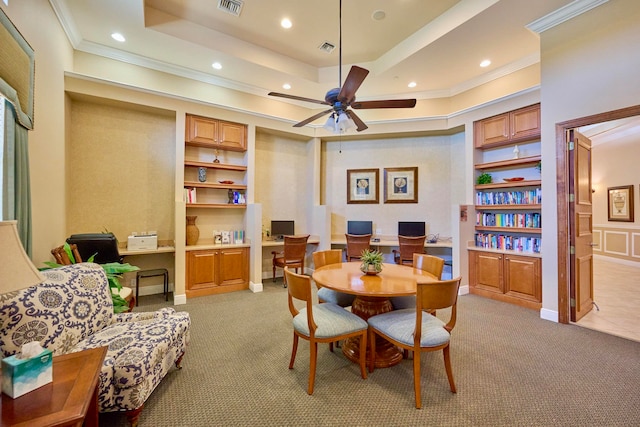 dining room with a raised ceiling, light carpet, built in features, and ornamental molding