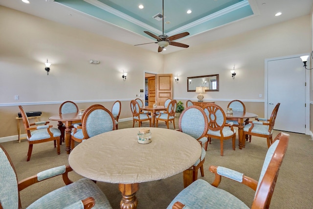 carpeted dining area with a tray ceiling, ceiling fan, and crown molding