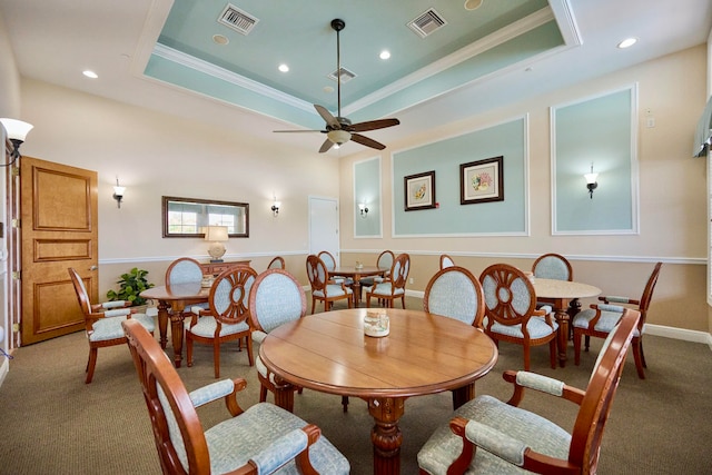 carpeted dining area featuring a tray ceiling, crown molding, and ceiling fan