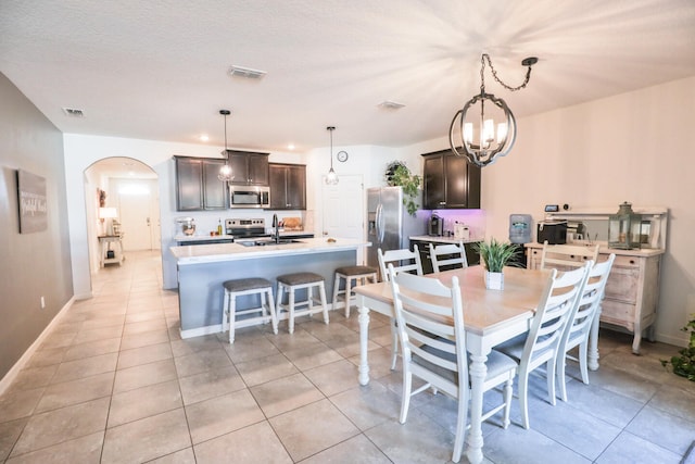 dining space with sink, light tile patterned floors, a textured ceiling, and a chandelier