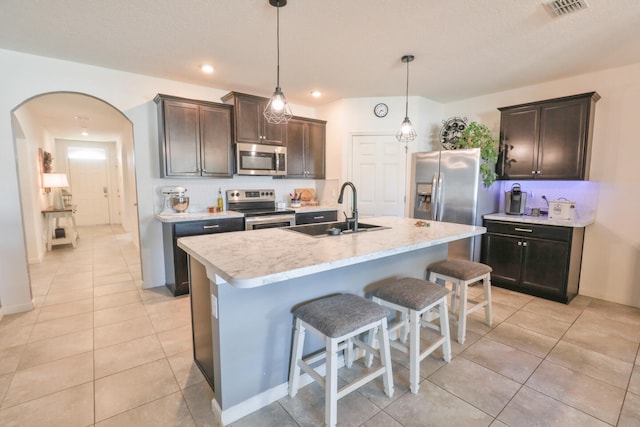 kitchen featuring sink, hanging light fixtures, a center island with sink, dark brown cabinets, and appliances with stainless steel finishes