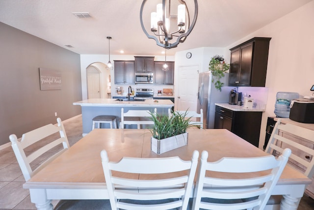 tiled dining room with sink and an inviting chandelier