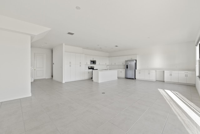 unfurnished living room with light tile patterned flooring and sink