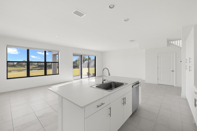 kitchen with stainless steel dishwasher, sink, a center island with sink, white cabinetry, and light tile patterned flooring