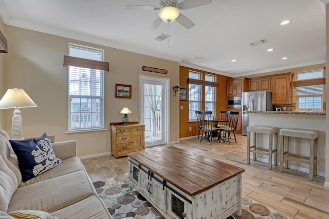 living room with ceiling fan, crown molding, and light hardwood / wood-style floors