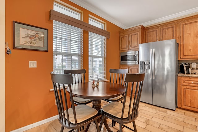 dining room with crown molding and light hardwood / wood-style flooring