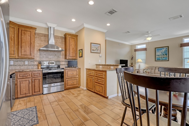 kitchen with plenty of natural light, light hardwood / wood-style floors, wall chimney range hood, and appliances with stainless steel finishes