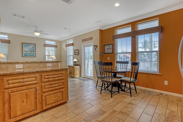 kitchen with ceiling fan, light stone countertops, and ornamental molding