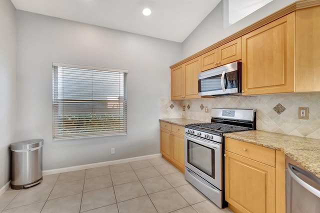 kitchen with lofted ceiling, stainless steel appliances, and light brown cabinetry