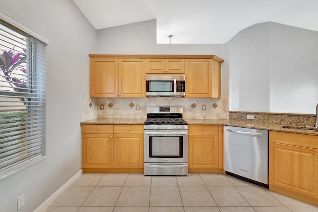 kitchen featuring light stone counters, light tile patterned flooring, lofted ceiling, and appliances with stainless steel finishes