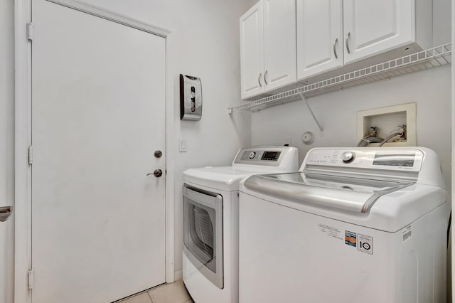 washroom featuring washing machine and dryer, light tile patterned floors, and cabinets