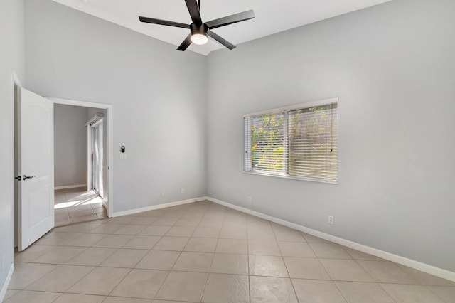 spare room with ceiling fan, light tile patterned flooring, and a high ceiling