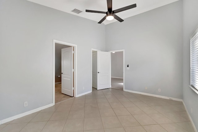 spare room featuring ceiling fan, light tile patterned floors, and a high ceiling