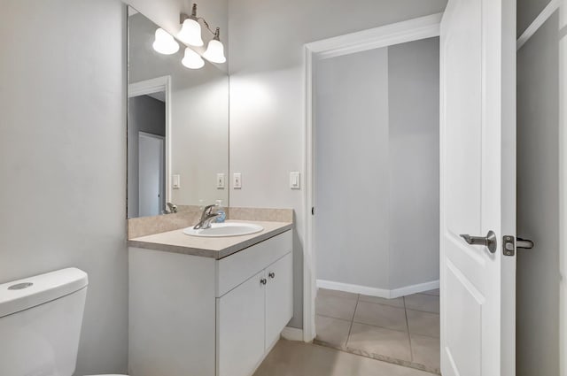 bathroom with toilet, vanity, and tile patterned floors