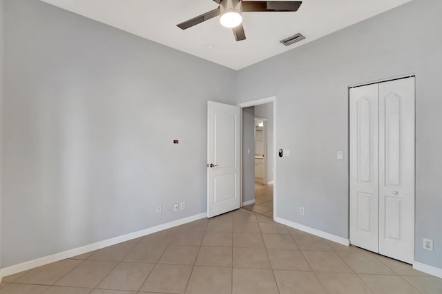 unfurnished bedroom with ceiling fan, light tile patterned flooring, and a closet