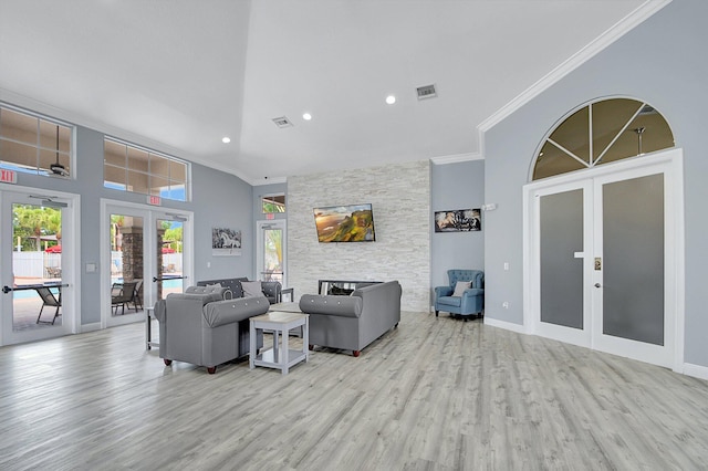 living room with light wood-type flooring, french doors, a towering ceiling, and ornamental molding