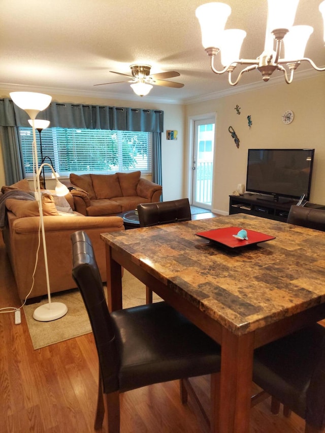 dining space with hardwood / wood-style floors, ceiling fan with notable chandelier, and crown molding