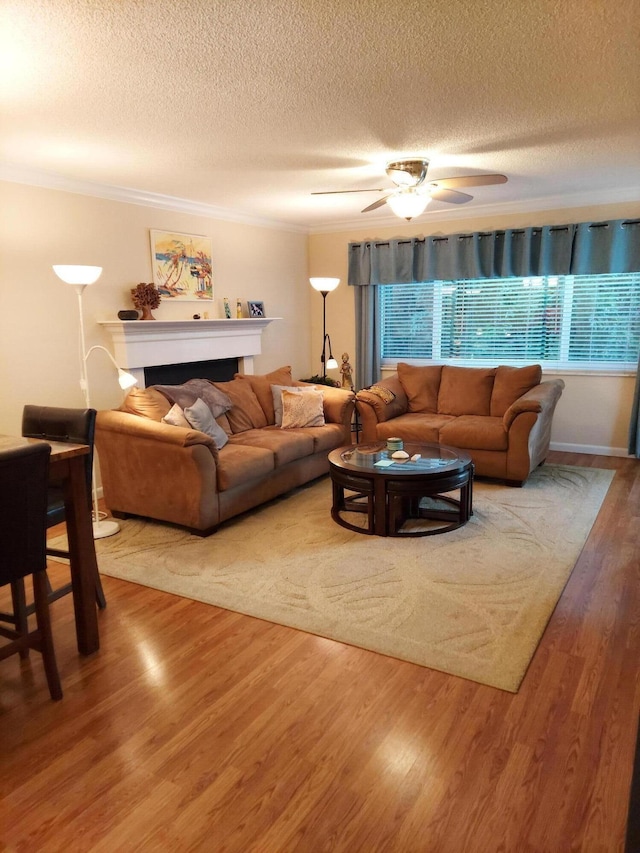 living room with a textured ceiling, hardwood / wood-style flooring, ceiling fan, and crown molding