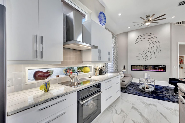 kitchen with black appliances, wall chimney exhaust hood, decorative backsplash, light stone counters, and white cabinetry