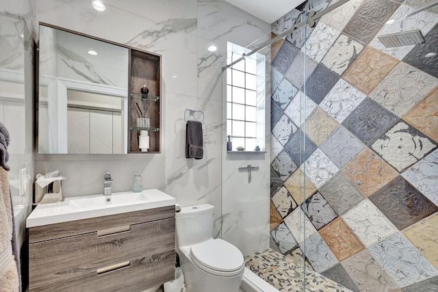 bathroom featuring vanity, toilet, a tile shower, and tile walls