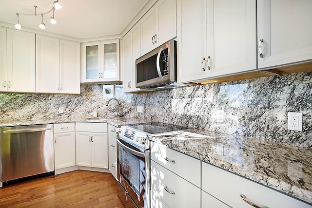 kitchen featuring light stone countertops, light hardwood / wood-style flooring, white cabinets, and appliances with stainless steel finishes